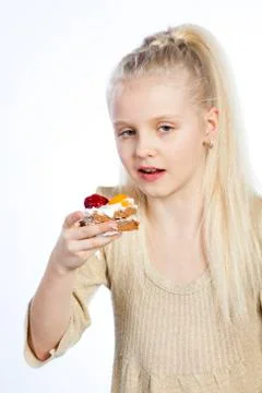 Girl eats a cake on white background. Fotos Stock