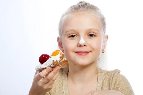 Girl eats a cake on white background. Фото