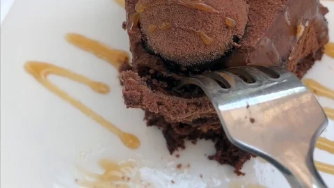 Girl eats a chocolate sponge cake topped with caramel sauce Stock Footage 109213526