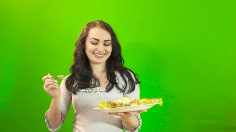 Girl eats on a green background Stock Footage 61787304