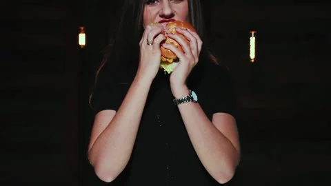 The girl eats a hamburger with appetite. Video stock 154454224