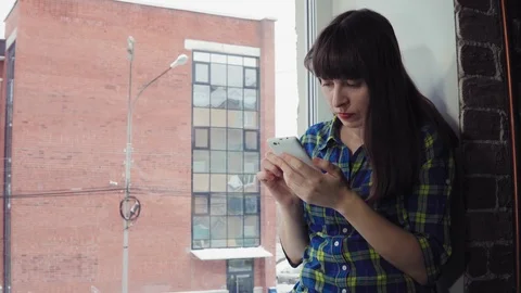 The girl eats instant noodles sitting on a windowsill against a brick building. Stock Footage 99043833