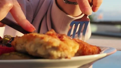 A girl eats meat in a restaurant against the backdrop of the sea and palm trees Stock-Footage 332132276