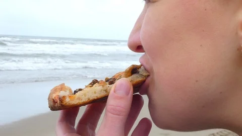 The girl eats a pizza on the beach.. Stock Footage 108468093
