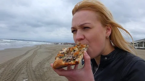 The girl eats a pizza on the beach Stock Footage 108468186