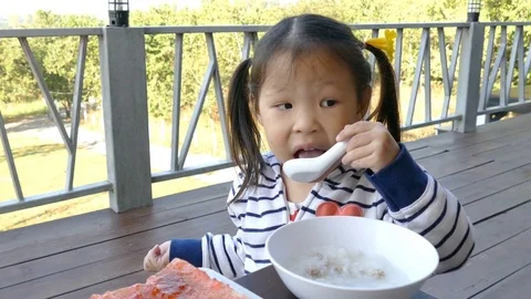 Girl eats rice soup for breakfast Stock Footage 73512432