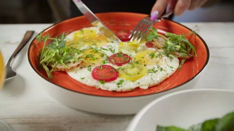 The girl eats scrambled eggs with tomatoes and herbs for breakfast Stock Footage 204023231