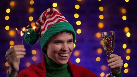 Girl in elf hat hat drinks champagne against the background of Christmas garland Stock Footage 256753109