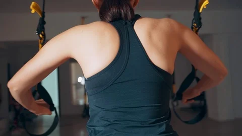 Girl is engaged in the hall using TRX loops. Exercise on the muscles of the Stock-Footage 115151523