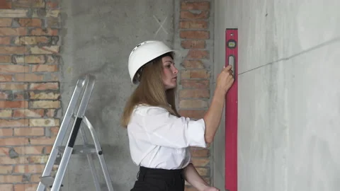 Girl engineer builder checks the evenness of the wall with a level. Stock Footage 183884077