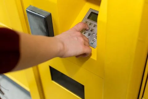The girl enters the numeric pickup code for the parcel into the parcel machine Stock Photos