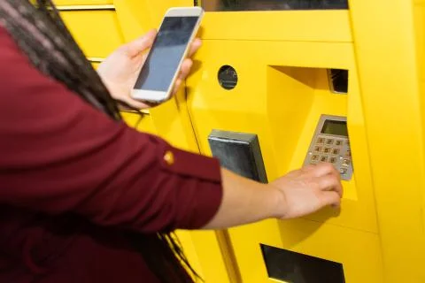 The girl enters the numeric pickup code for the parcel into the parcel machine 写真素材