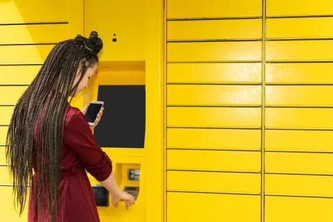 The girl enters the numeric pickup code for the parcel into the parcel machine 写真素材