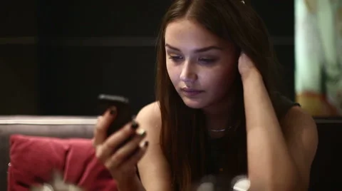A girl in the evening in a cafe reading something on your smartphone Stock Footage 47655846