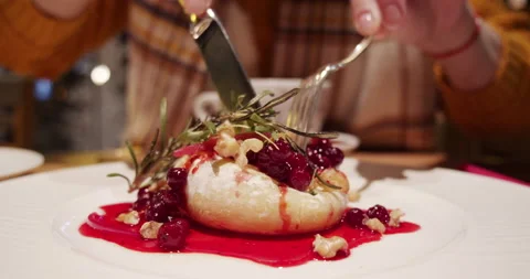 A girl in an evening restaurant appetizingly eats a French dish brie cheese with Stock Footage 165622914