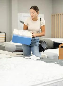 Girl examines samples structure of spring mattress in furniture store. Stock-Fotos
