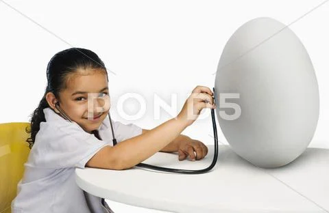 Girl examining a egg with a stethoscope Stock Photos