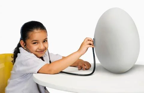 Girl examining a egg with a stethoscope Stock Photos