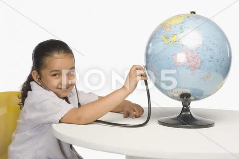 Girl examining a globe with a stethoscope Stock Photos