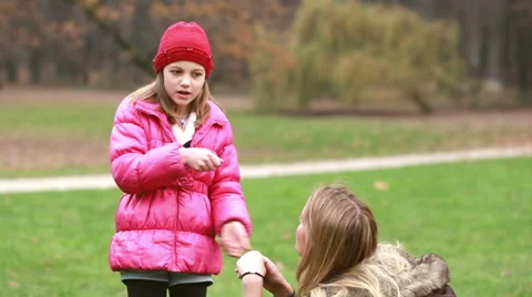 Girl explaining game to her mom in park, dad coming and hugging her Stock Footage 59554647