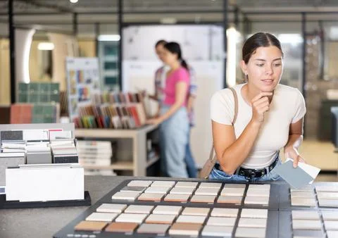 Girl exploring tile samples on display board in building hypermarket Fotos de archivo