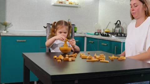 Girl is exploring wooden cubes at a table in a colorful preschool room Stock Footage 322897497