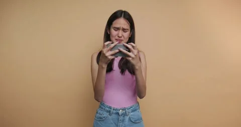 Girl expresses disappointment while playing a mobile game indoors in casual.. Stock Footage 317328291