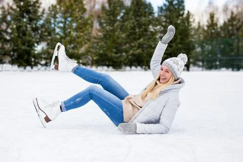 Girl falling down while ice skating at winter rink Stockfoto's