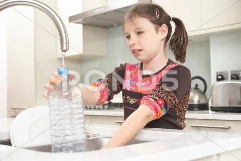 Girl Filling Up Water Bottle In Kitchen