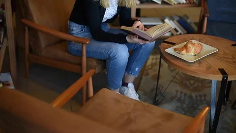 Girl finding words in book while eating croissant Stock Footage 73120607