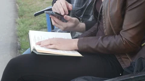 Girl flipping through the book while the guy is using the phone Video stock 90778098