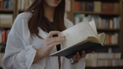 Girl flips a book in the library Stock Footage 252062464