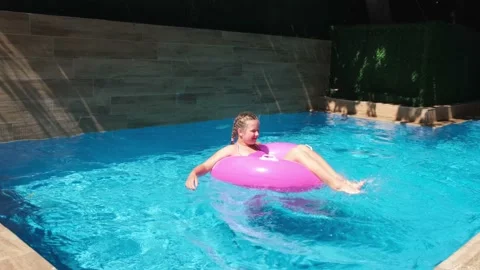 Girl floating on pink inflatable ring and diving under water. Traveling and Stock Footage 160962697