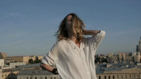 Girl with flying hair posing for the camera on the roof of the building. Stock Footage 60989953