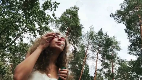 Girl in forest blows bubbles Stock Footage 79687419