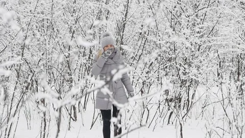 Girl in the forest during a snowfall dances and jumps, catches snowflakes . Video stock 130640928