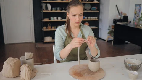 The girl forms a handle for a clay cup. Creating cup of white clay Stock Footage 119544535