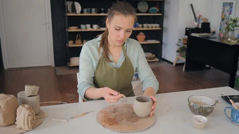 The girl forms a handle for a clay cup. Creating cup of white clay 库存影片 119544574