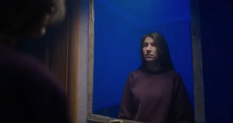 Girl in front of mirror with subtle blue reflection, medium close-up, blinking Stock Footage 325092073