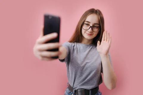 Girl gesturing hello while having video chat on smartphone Stock Photos