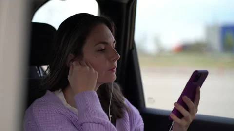 Girl gets bored while riding in a taxi and wants to listen to music from her Stock Footage 209632694