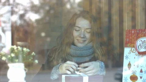 A girl with a gift in a cafe. Видео 82099672