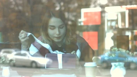 A girl with a gift in a cafe. Stockbeeldmateriaal 82099780
