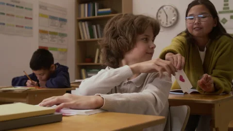 Girl Giving Card to Smiling Boy in School Stock Footage 328324853