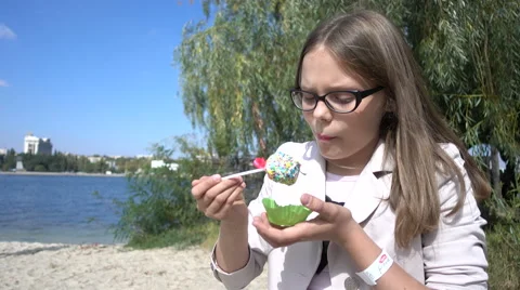 Girl in Glasses eats Cake outdoors by the River Stock Footage