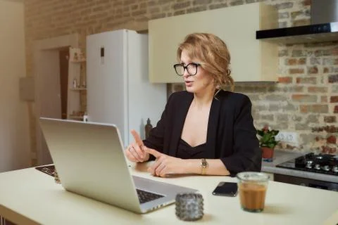 A girl in glasses gesturing while talking to her colleagues in a video call. Stock Photos