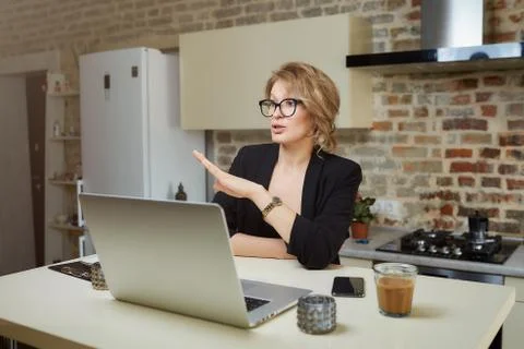 A girl in glasses gesturing while talking to her colleagues in a video call. Stock Photos