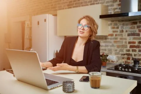 A girl in glasses gesturing while talking to her colleagues in a video call. Stock Photos