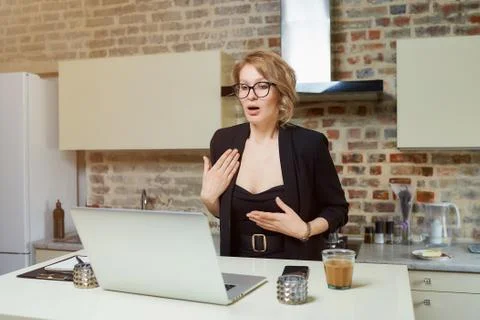 A girl in glasses gesturing while talking to her colleagues in a video call. Stock Photos