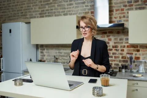 A girl in glasses gesturing while talking to her colleagues in a video call. Stock Photos